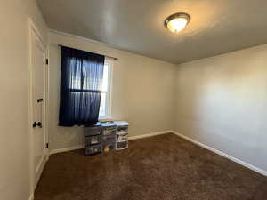 Bedroom with baseboards and dark colored carpet