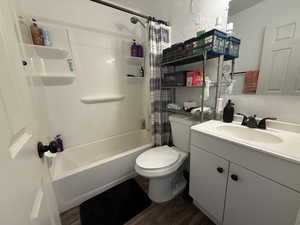 Full bathroom with vanity, shower / bath combo, a textured wall, and dark wood finished floors