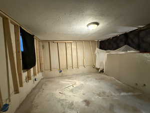 Unfinished basement bedroom with a textured ceiling