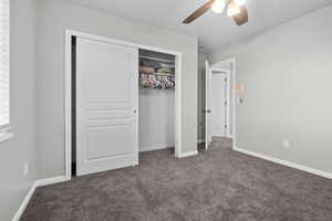 Unfurnished bedroom with a closet, carpet floors, and a ceiling fan