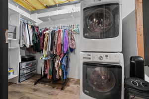 Walk-in closet featuring the included, stacked washing machine and dryer and wood finished floors