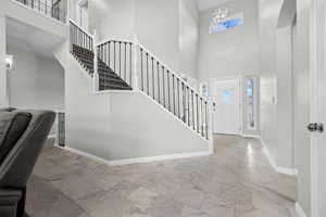 Foyer with a high ceiling, stairs, plenty of natural light, and marble finish flooring