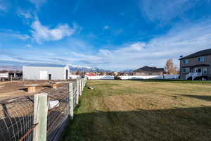 View of yard, separate pasture, mountain view, a detached garage/workshop building, and a residential view