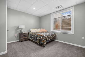 Carpeted bedroom featuring a drop ceiling and baseboards