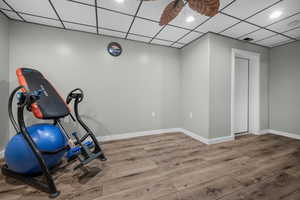 Workout area featuring a drop ceiling and wood finished floors