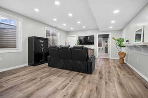 Basement living room featuring light wood-style floors, recessed lighting, and plenty of natural light