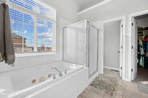 Full bath featuring a spacious closet, a jetted tub, a shower stall, and light tile finish floors