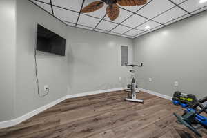 Exercise room featuring a paneled ceiling, wood finished floors, electric panel, recessed lighting, and ceiling fan
