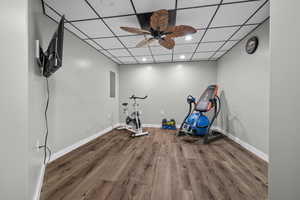Workout room featuring recessed lighting, a drop ceiling, wood finished floors, a ceiling fan, and electric panel