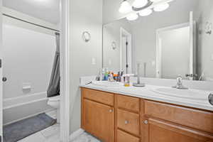 Full bathroom featuring double vanity, shower / tub combo, and light marble finish floors