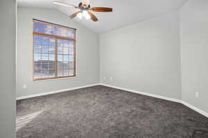 Unfurnished room with lofted ceiling, dark colored carpet, and a ceiling fan