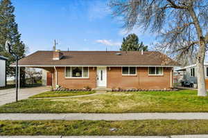 View of front of property featuring a front yard, a chimney, an attached carport, and driveway