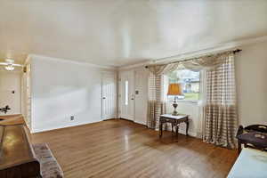 Entryway with crown molding and wood finished floors