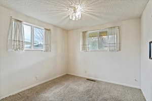 Carpeted empty room featuring a textured ceiling and baseboards