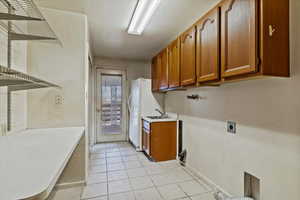 Washroom with light tile patterned floors, hookup for an electric dryer, and cabinet space