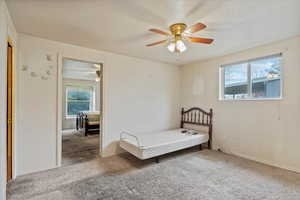 Carpeted bedroom featuring a textured ceiling and ceiling fan