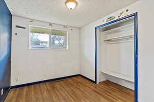 Unfurnished bedroom with wood finished floors, a textured ceiling, and a closet