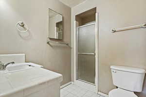 Bathroom featuring a stall shower, vanity, and light tile patterned floors