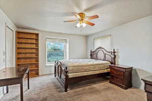 Bedroom featuring a textured ceiling, light carpet, and a ceiling fan