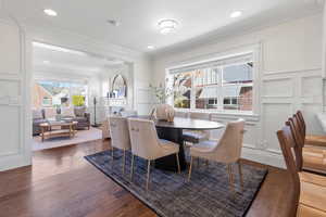 Dining space with a decorative wall, dark wood-type flooring, healthy amount of natural light, ornamental molding, and a fireplace