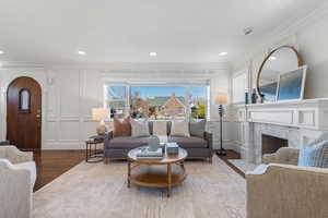 Living area featuring a decorative wall, a premium fireplace, crown molding, and wood finished floors