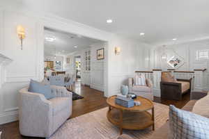Living room featuring a decorative wall, dark wood-style flooring, healthy amount of natural light, recessed lighting, and crown molding