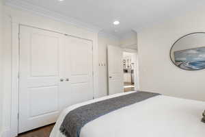 Bedroom featuring crown molding, wood finished floors, a closet, recessed lighting, and stainless steel refrigerator with ice dispenser
