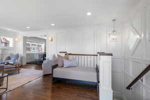 Sitting room with a decorative wall, crown molding, dark wood-style floors, and recessed lighting
