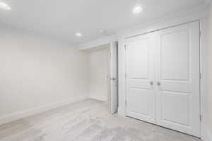 Unfurnished bedroom featuring light carpet, recessed lighting, ornamental molding, and a closet