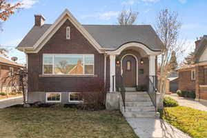 View of front of property featuring brick siding, a front lawn, and a chimney