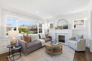 Living area featuring a decorative wall, crown molding, a high end fireplace, wood finished floors, and recessed lighting