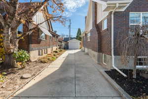 View of side of property with brick siding, an outdoor structure, a garage, and driveway