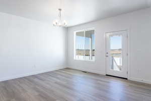 Unfurnished dining area featuring light wood-type flooring and a chandelier