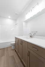Full bath with vanity, light wood-type flooring, and shower / bath combination