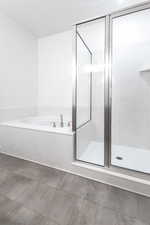 Bathroom featuring a marble finish shower and a bath