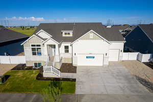 View of front of house with driveway, stone siding, roof with shingles, and an attached garage
