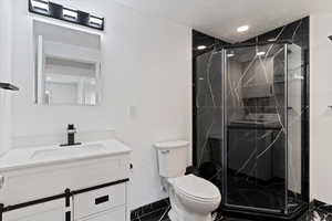 New bathroom featuring a marble finish shower, vanity, and a textured ceiling