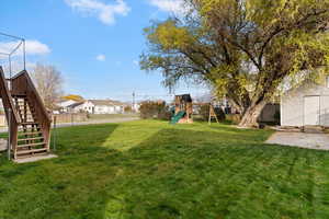 Fenced backyard with stairs, a residential view, a playground, a storage unit, and a patio area