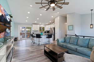 Open floor plan! Living room with vaulted ceiling, light wood-style floors, a ceiling fan, and recessed lighting
