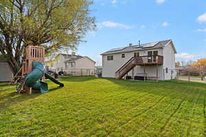 Back of property featuring a gate, stairs, a fenced backyard, solar panels, and a playground