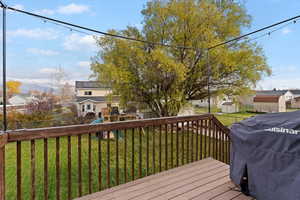 Wooden deck with a residential view, a playground, a fenced backyard, and a grill