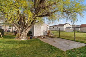 Fenced backyard with a storage unit and a patio area
