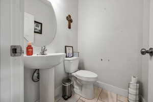 Half bath featuring toilet and baseboards
