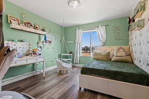 Bedroom with wood finished floors and an AC wall unit