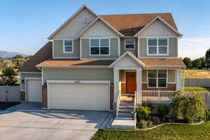 Craftsman-style home featuring a shingled roof, driveway, a porch, and a garage