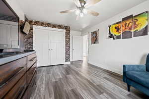 Sitting room with brick wall, light wood-style floors, and a ceiling fan