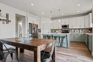 Dining room with light wood-type flooring and recessed lighting
