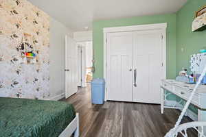 Bedroom featuring dark wood-style flooring and a closet