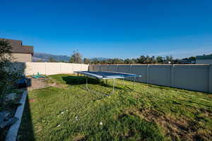 Fenced backyard featuring a trampoline and a mountain view