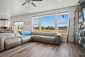 Living room with light wood finished floors, recessed lighting, a textured ceiling, and a ceiling fan